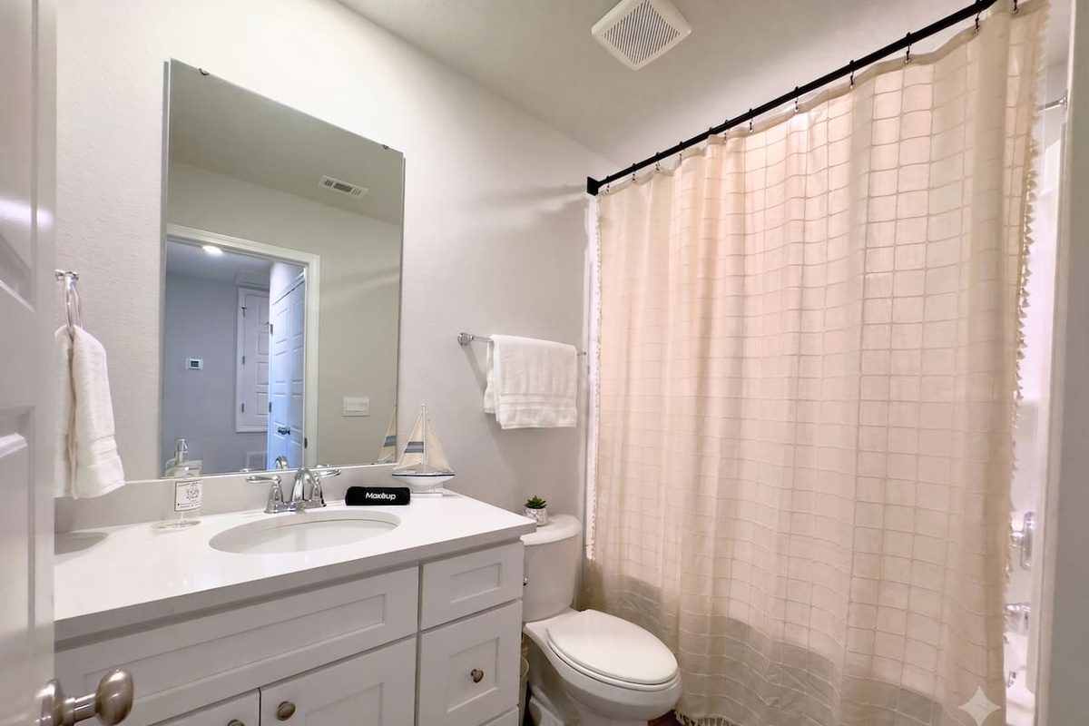 Warm water waits behind the curtain, cool counter beneath your hands as you get ready. Soft light through the window. Simple, tidy, easy to move through.