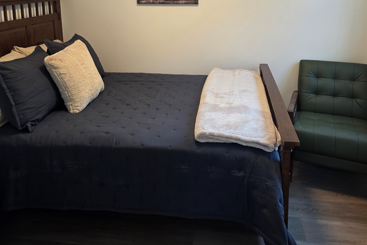 Bedroom on main floor includes a Queen Size Bed with night stand, closet space, chair and TV.