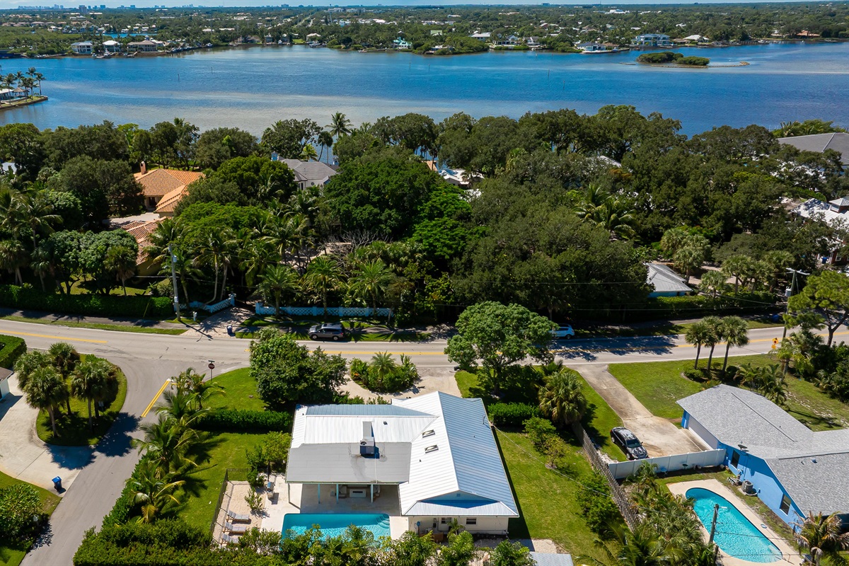 A stunning aerial view captures this luxury coastal retreat with a sparkling pool, manicured lawns, and lush tropical landscaping - offering the perfect blend of privacy, sophistication, and resort-style living just minutes from the beach.