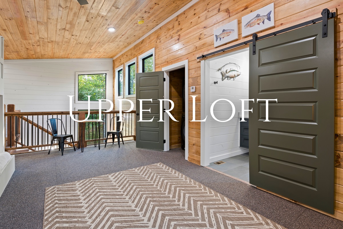 The upper loft offers a spacious and versatile area with sliding green doors