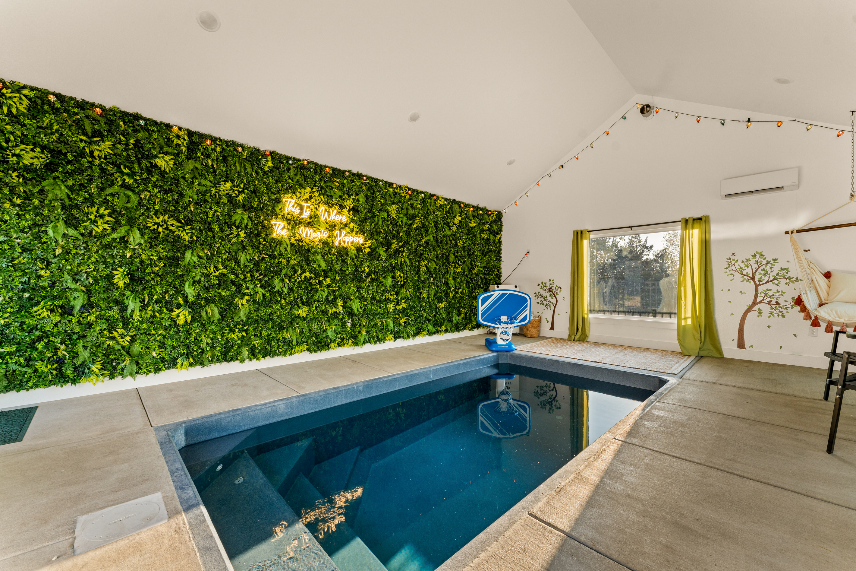 Bright windows and a lush greenery wall bring a fun, resort-like atmosphere to the private indoor pool house.