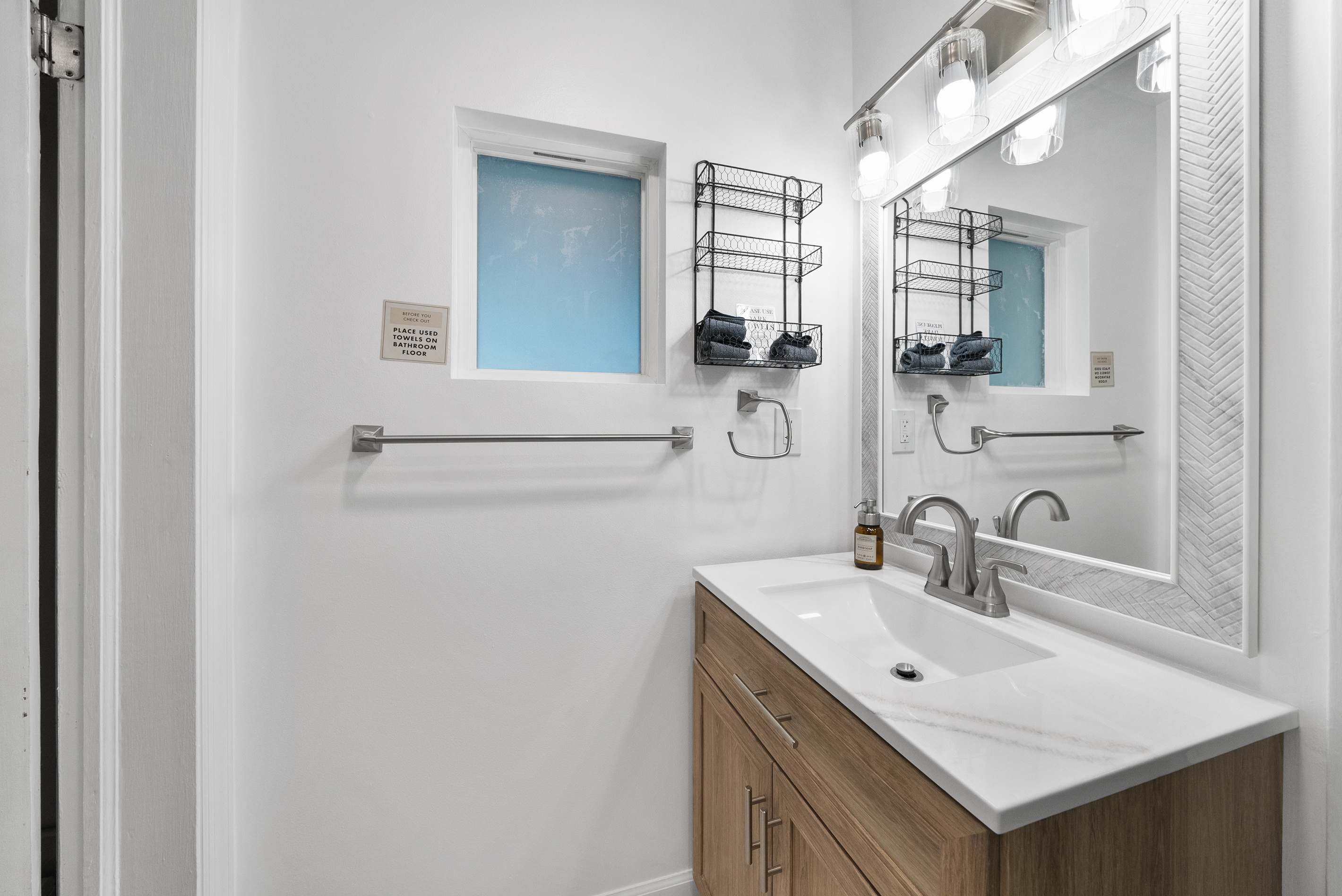 Bathroom #1, Jack and Jill — brand-new wood vanity, herringbone mirror, and finishes in the renovated bath