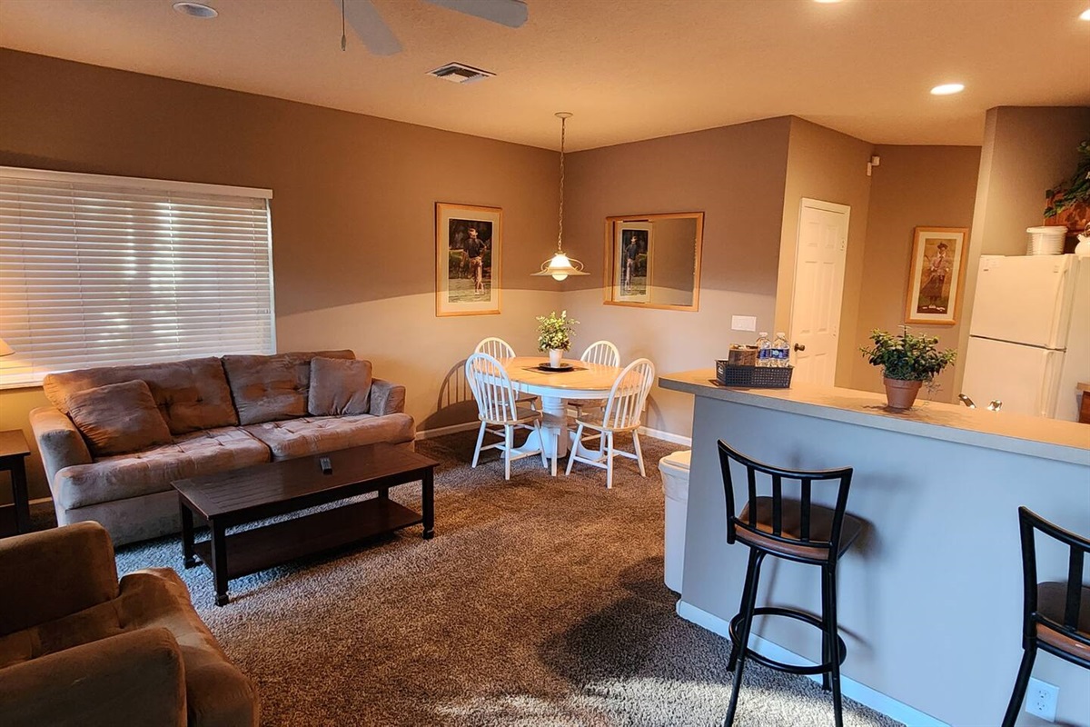 Open living and dining space with breakfast bar seating, natural light, and a relaxed, welcoming layout.