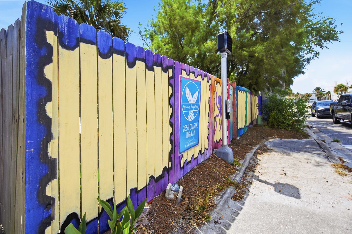 The mural runs the whole length of the fence in yellows and violets, a proper piece of Vilano Beach folk art. Guests photograph it constantly, which probably tells you most of what you need to know about this street.
