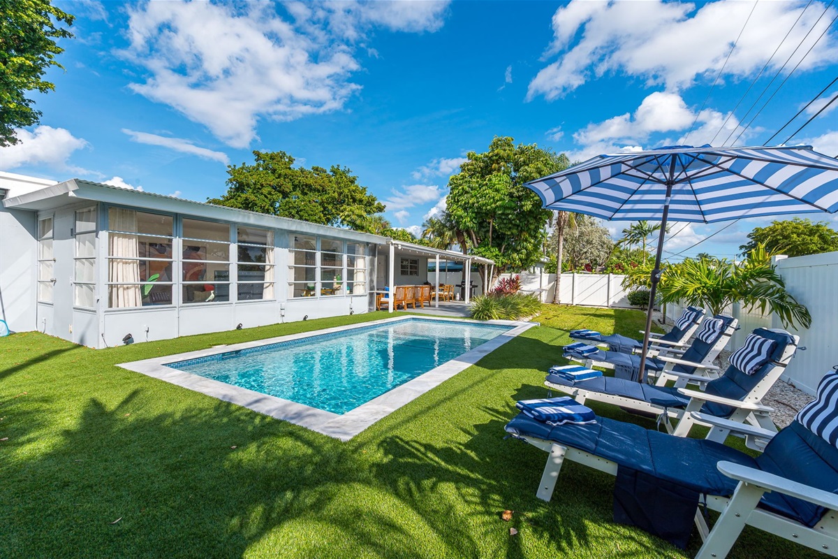 Dive into luxury with a sparkling heated saltwater pool, surrounded by lush palms, chic loungers, and modern turf for the perfect resort-style backyard escape.