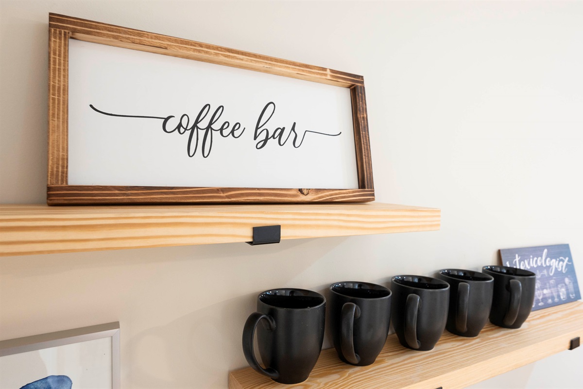 A cozy coffee bar setup with stylish black mugs on wooden shelves, perfect for a warm and inviting space.