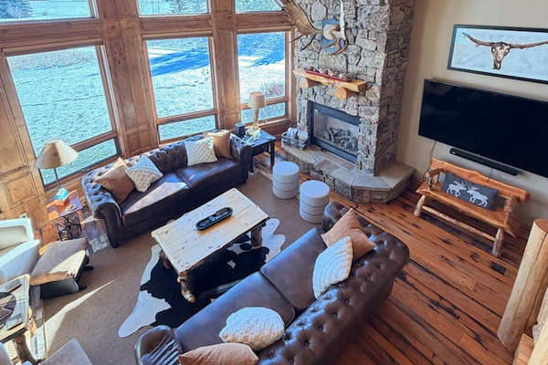 This main-level living room boasts massive floor-to-ceiling windows with stunning mountain views!