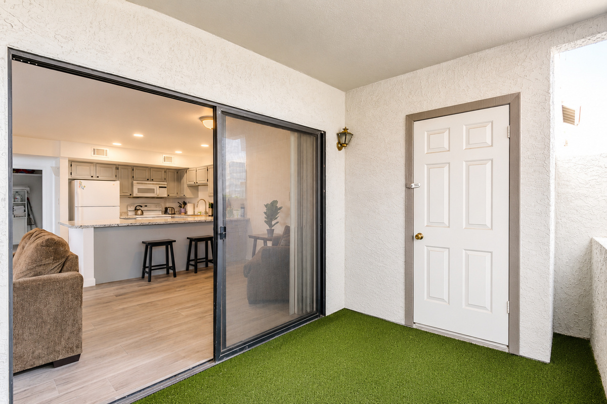 Private covered patio with turf flooring, storage closet, and sliding door access back into the living room and kitchen.
