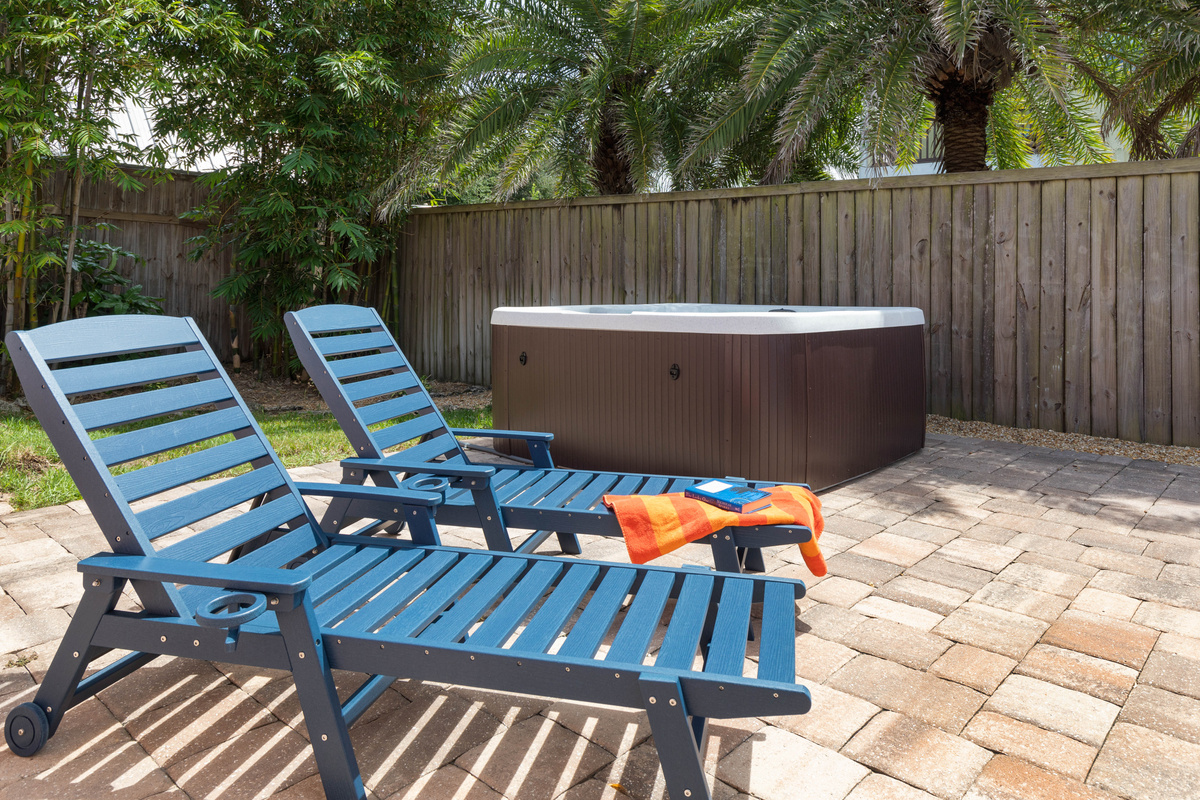 Two navy chaise loungers sit near the hot tub, an easy place to read, sunbathe and warm up between swims.