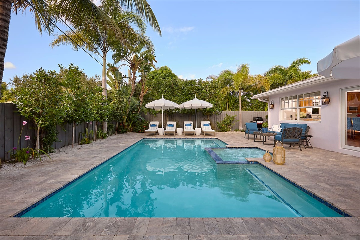 Enjoy a private backyard featuring a gorgeous pool and spa surrounded by lush tropical landscaping, a cozy conversation area with comfortable furniture, ultra-comfortable lounge chairs with thick, plush cushions, and an outdoor dining table for four.