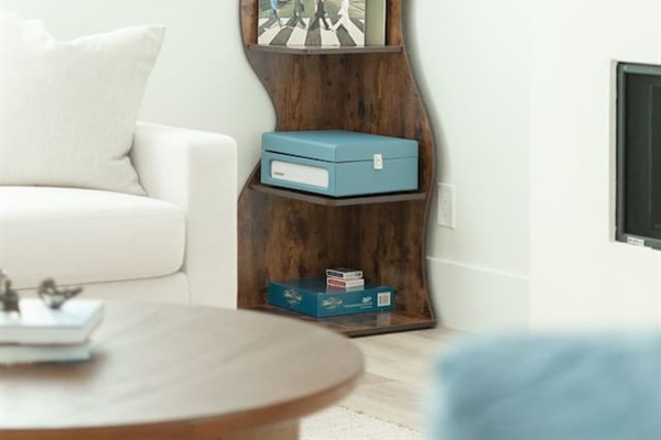 Curved wooden shelf with books, decor, and records adds character and charm to the living room, blending function with style.