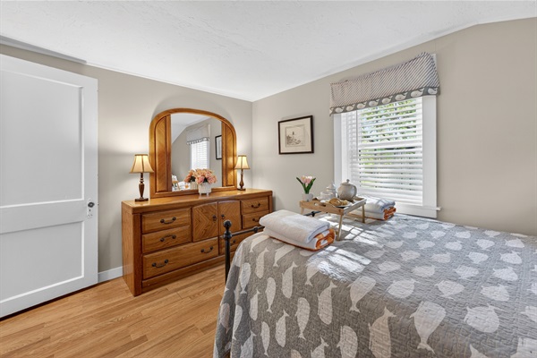 The third bedroom is a quiet haven, complete with a cozy queen bed and a vanity mirror made for restful nights.