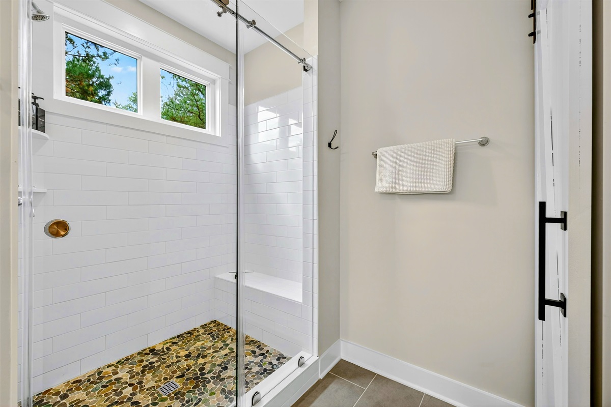 Guests will love the large shower with sliding glass barn style doors, pebble floors and the natural light that comes in from the windows!