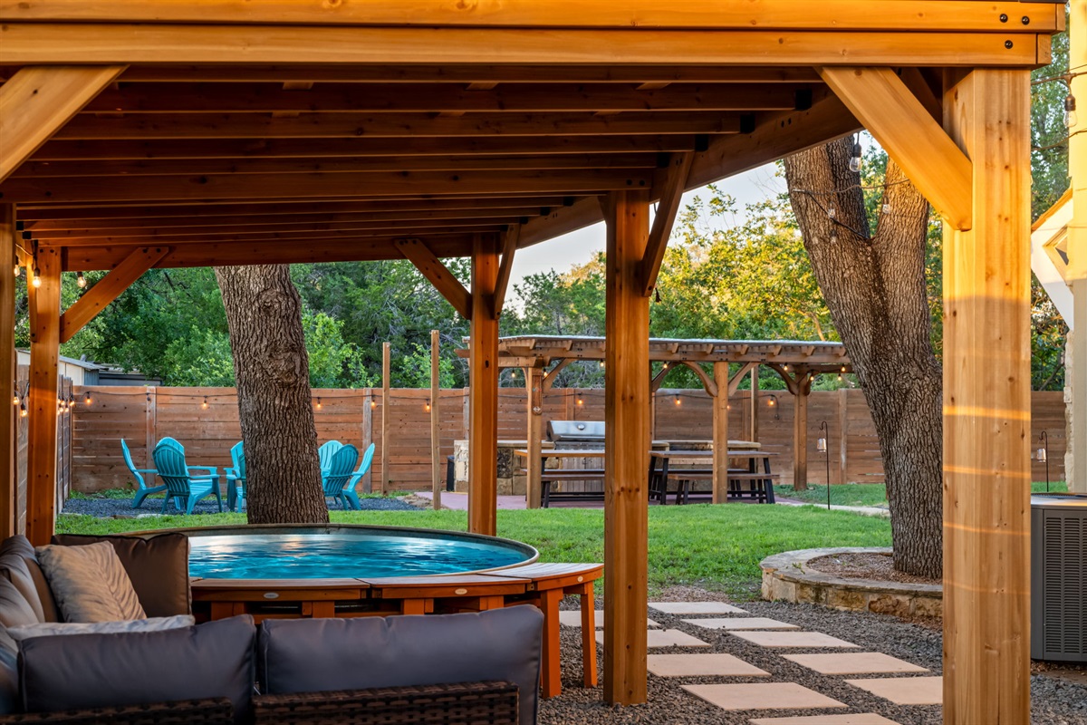 Slip into the hot tub beneath the trees and let the quiet evening settle around you. With cozy lounge seating, soft string lights, and open-air dining nearby, every moment feels effortlessly relaxing.
