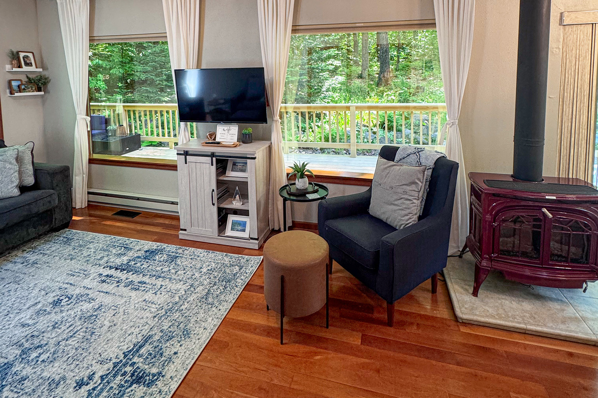 Main cottage living room view out windows- two huge panoramic mirror reflective windows overlooking the woods