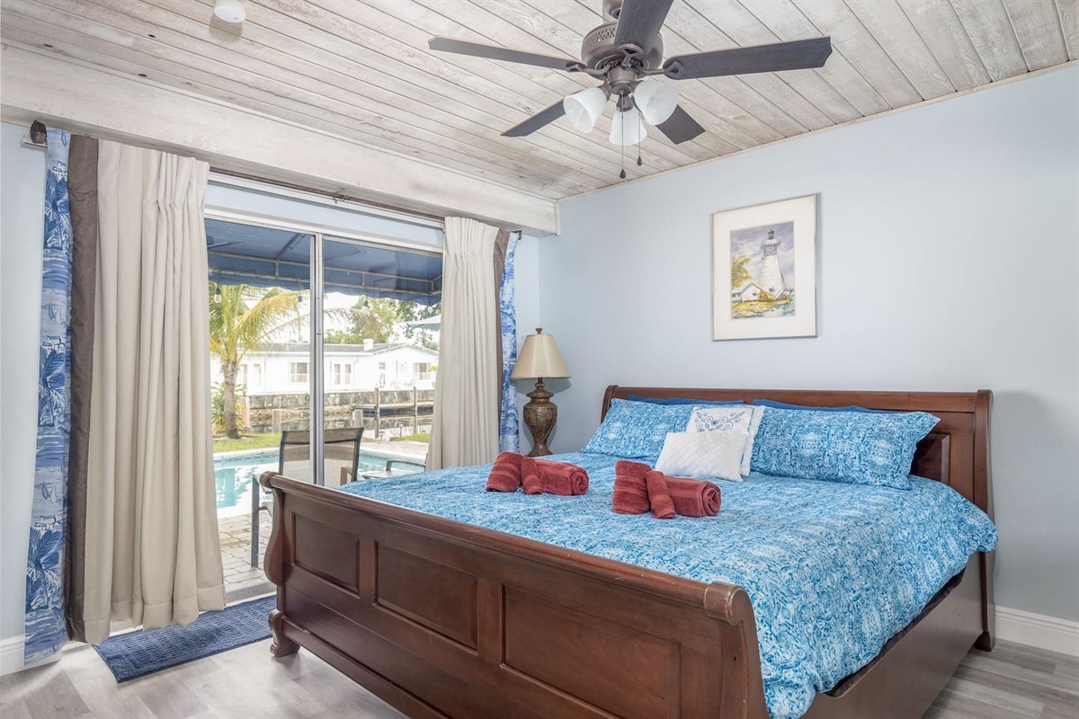 Junior Suite (Bedroom #2) with gorgeous view of the Bahama Canal! King-size sleigh bed,direct pool & backyard access, ceiling fan, dresser and closet, 45” smart TV with freeNetflix. Wide doorway.