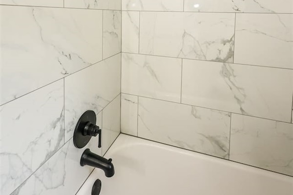 A stylish full bathroom with a shower tub, featuring a minimalist design that emphasizes simplicity and comfort.