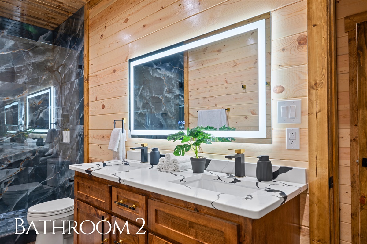 The nearby bathroom includes a wide vanity with plenty of room for getting ready, along with warm wood finishes that carry the cabin’s inviting style throughout the space.