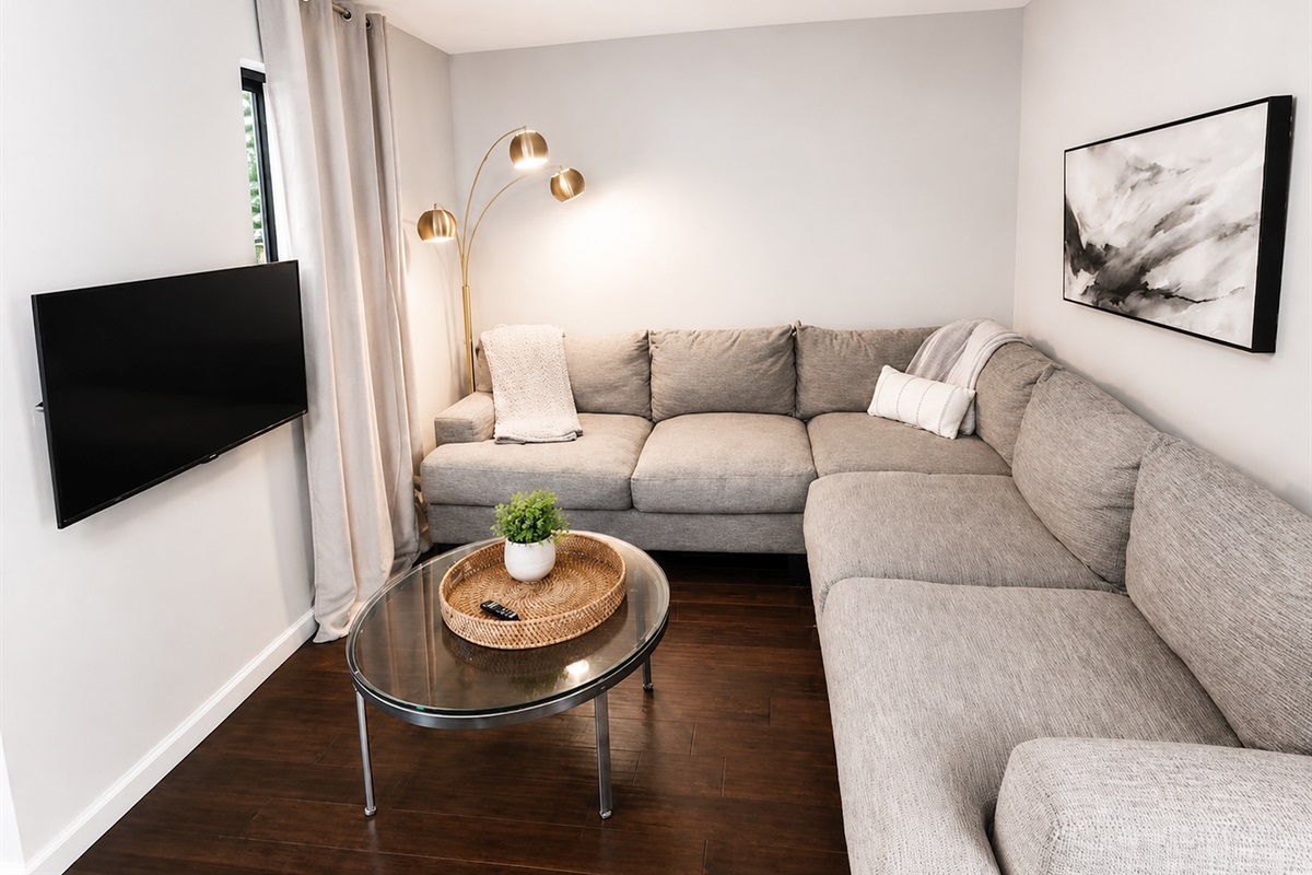 Cozy secondary lounge/media room with oversized sectional and smart TV — ideal for movie nights or kids’ hangouts