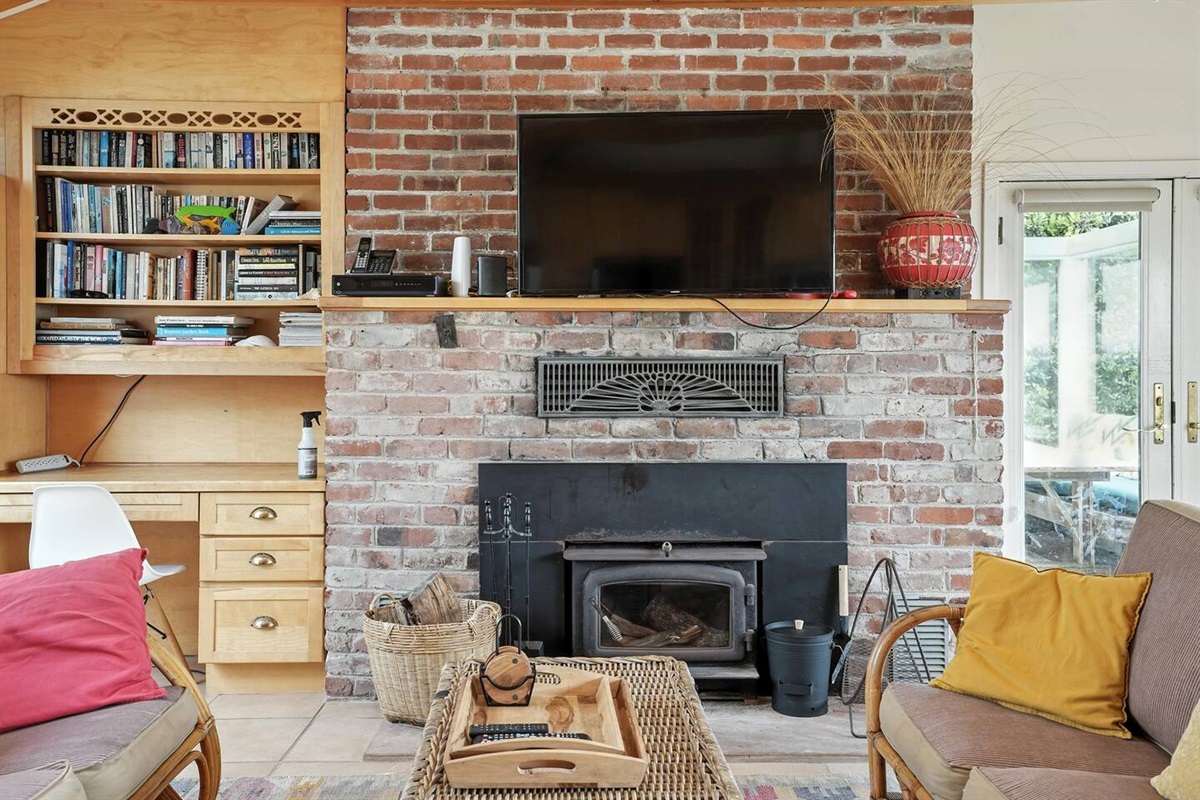 - Cozy living space with brick fireplace, mounted TV, and built in bookshelves  
- Comfortable seating and warm accents make it perfect for relaxation  
- Ideal for unwinding with a good book or movie after a day by the coast  