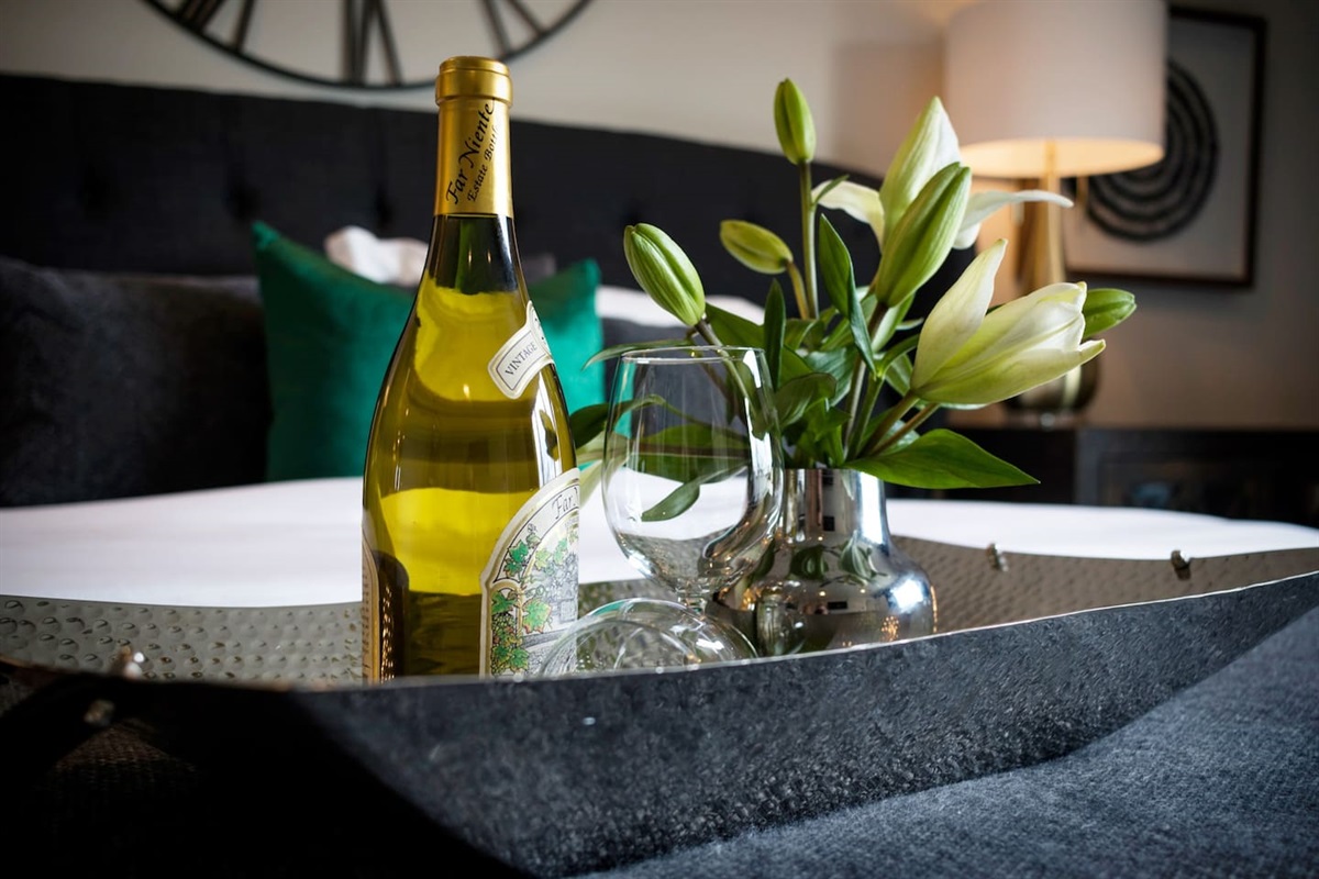 - Polished tray with chilled wine, glasses, and fresh lilies greets your arrival in style - Set against plush bedding & designer pillows for an elegant first impression - Perfect touch for special moments, honeymoons, or just a night of pampered comfort