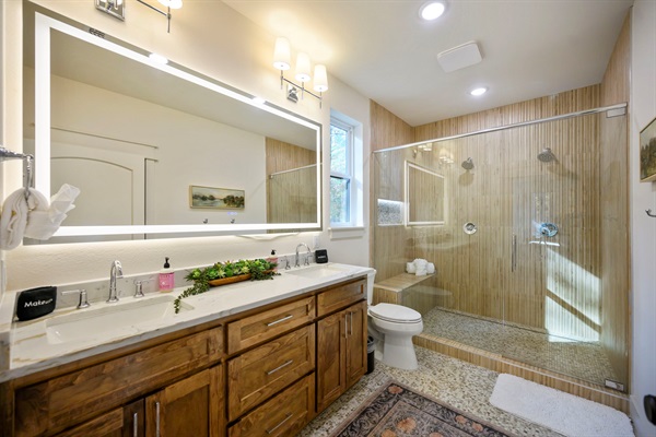 Spacious bathroom with double vanity, LED mirror, large walk-in shower, and warm rustic finishes—perfect for relaxing after your Broken Bow adventures. 🌲🛁