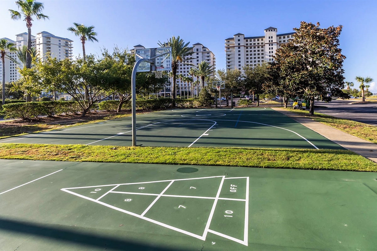 Enjoying the vibrant recreational amenities with a well-maintained basketball court and shuffleboard area, perfect for active leisure under the clear sky.