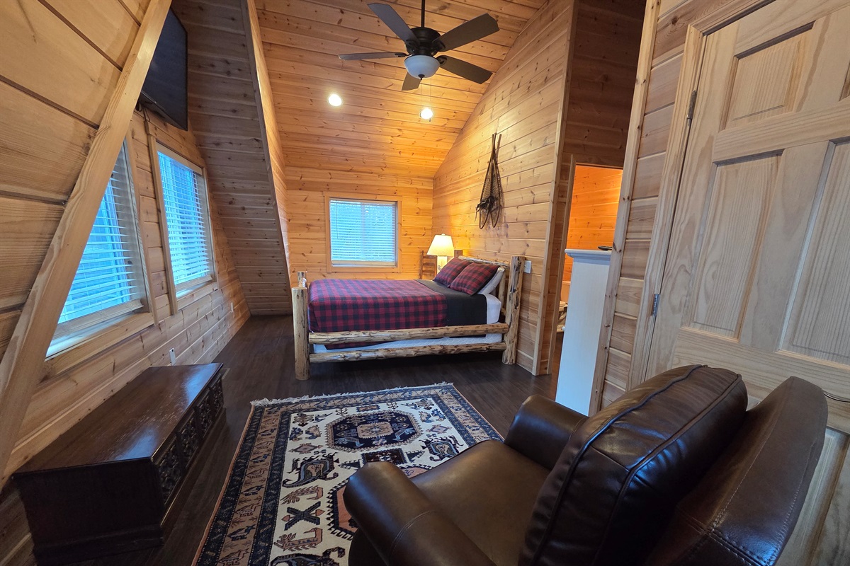 Upstairs, the second bedroom features a comfortable queen-size bed, a cozy chair, and a Smart TV for streaming.