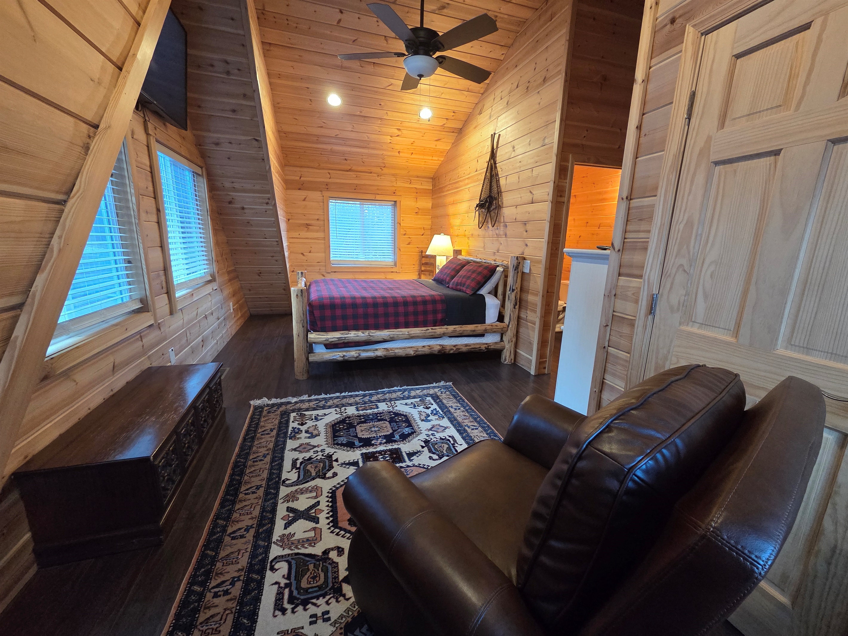 Upstairs, the second bedroom features a comfortable queen-size bed, a cozy chair, and a Smart TV for streaming.