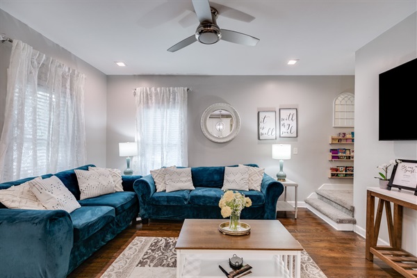 Step into a bright and inviting living area featuring a smart TV, stylish decor, and a comfy velvet sofa — perfect for relaxing after a day of exploring.