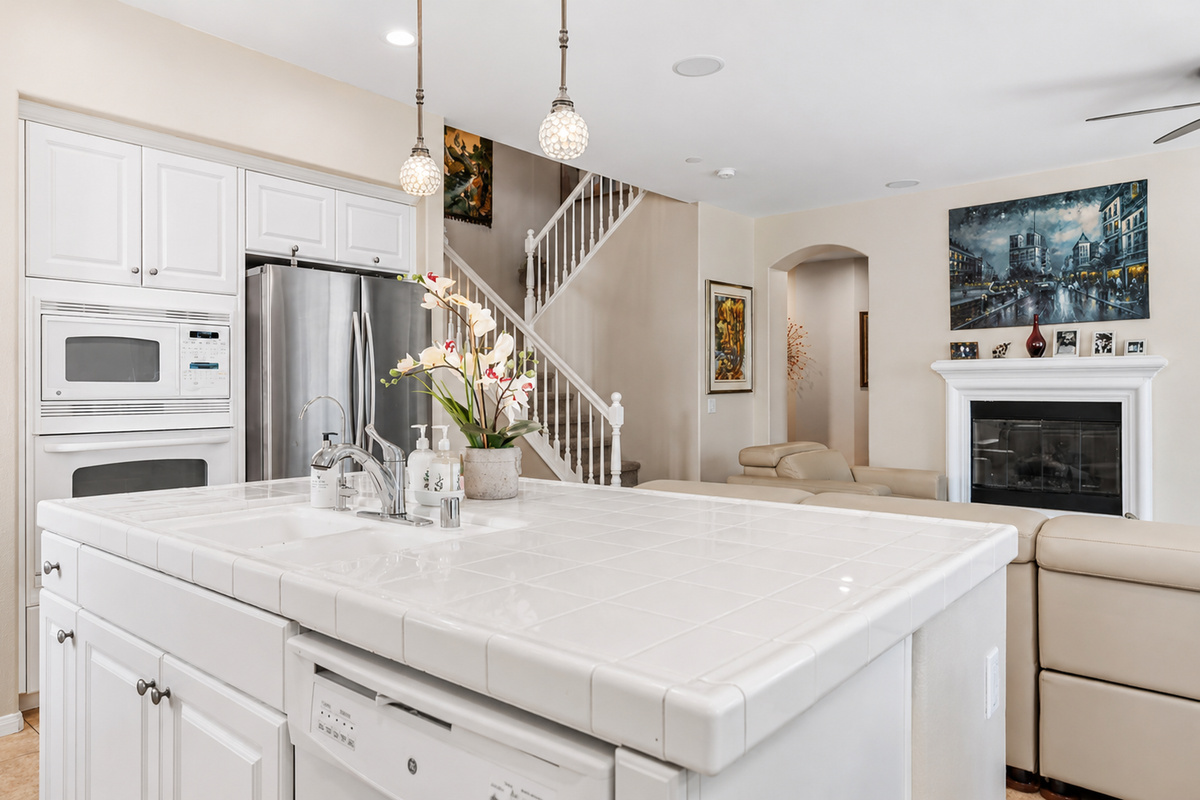 Kitchen island with lots of counter space, double ovens, and an open view to living room and stairs leading to the second level of the home 
