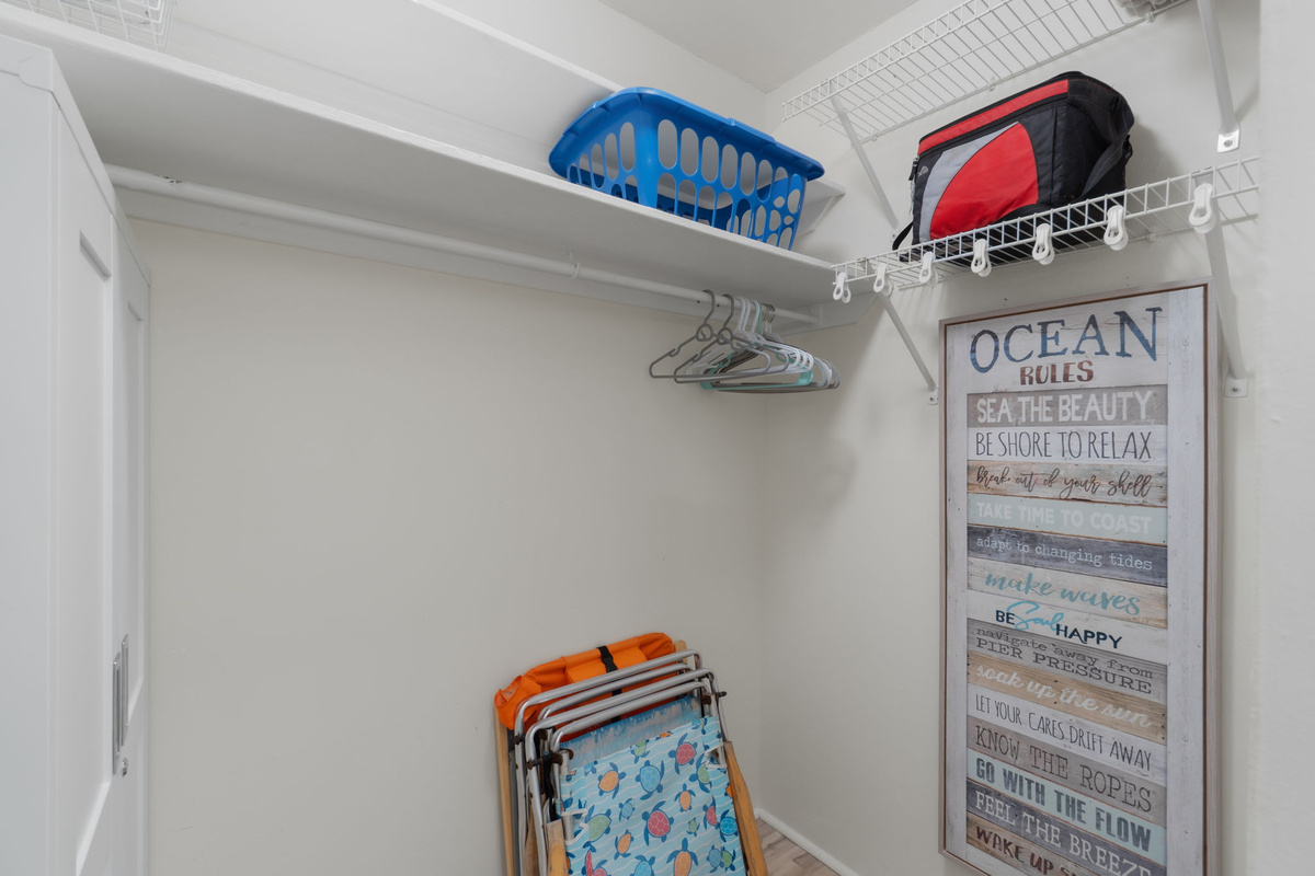 Walk in closet with hanging racks, shelves, and extra beach chairs and beach cooler for your use. 