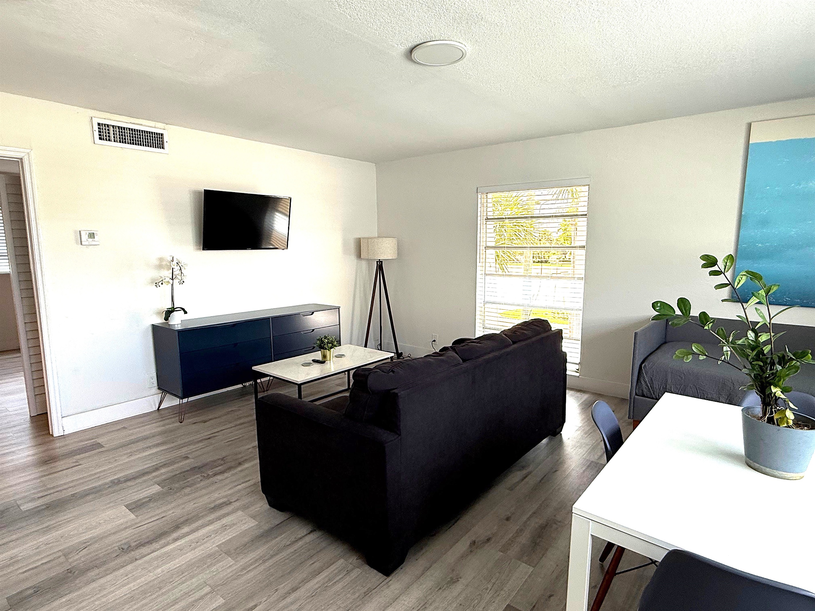 View showing smart TV, lounge chair and large window. Queen sofa bed that sleeps two guests.