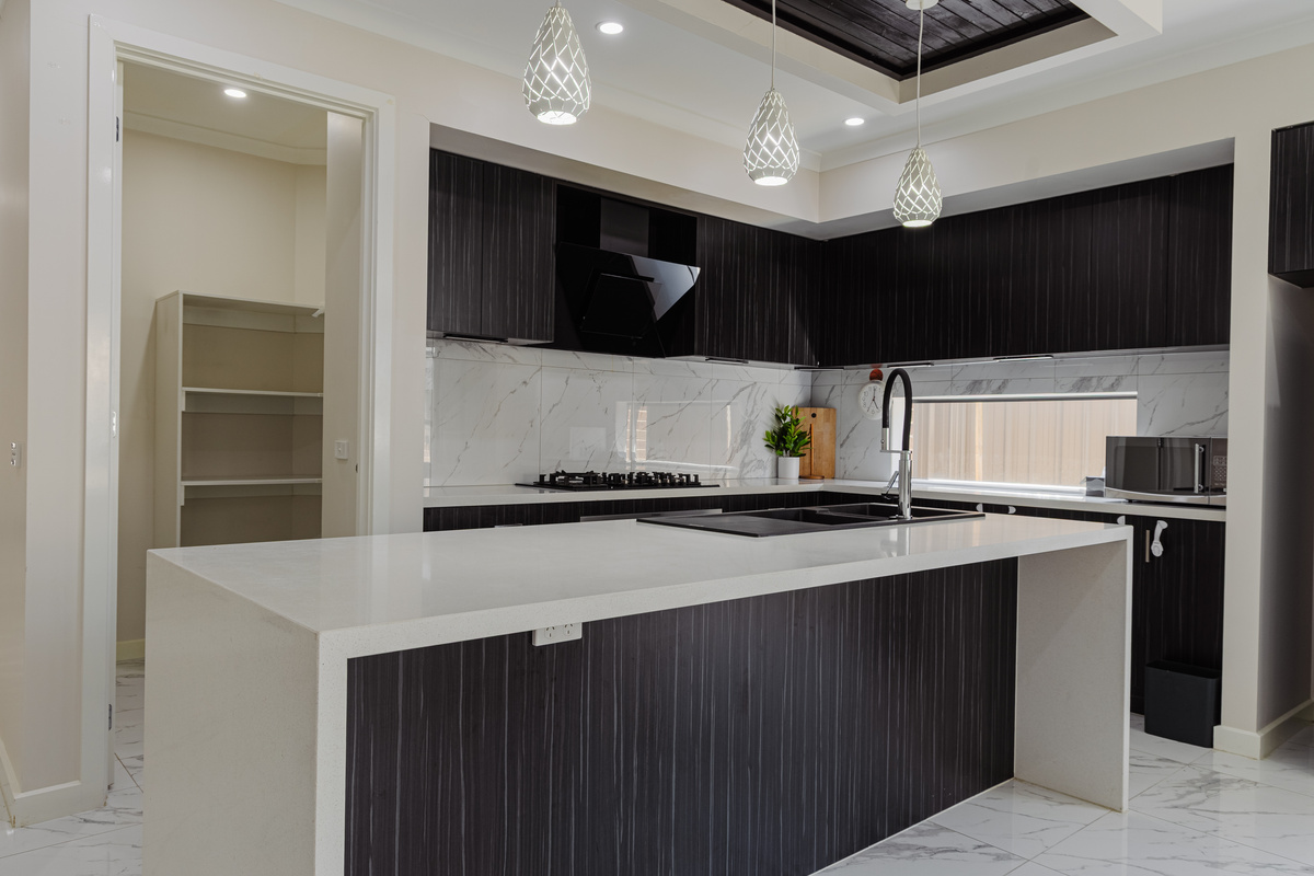 Kitchen with large island bench, gas cooktop, oven, rangehood and walk-in pantry.