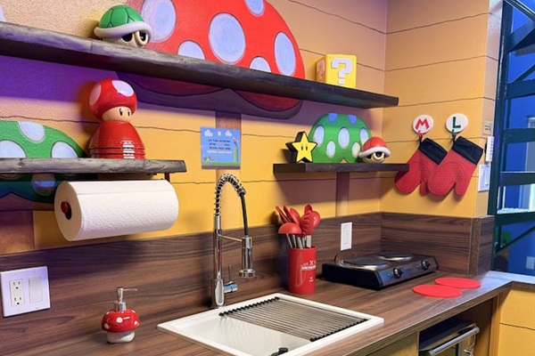 Playful Mario kitchen counter at Mario's Mini Mansion, Clermont, FL! Sink with flexible faucet, mushroom shelves, Toad figurine, and colorful Super Mario details make cooking and cleanup an exciting adventure for kids and adults.