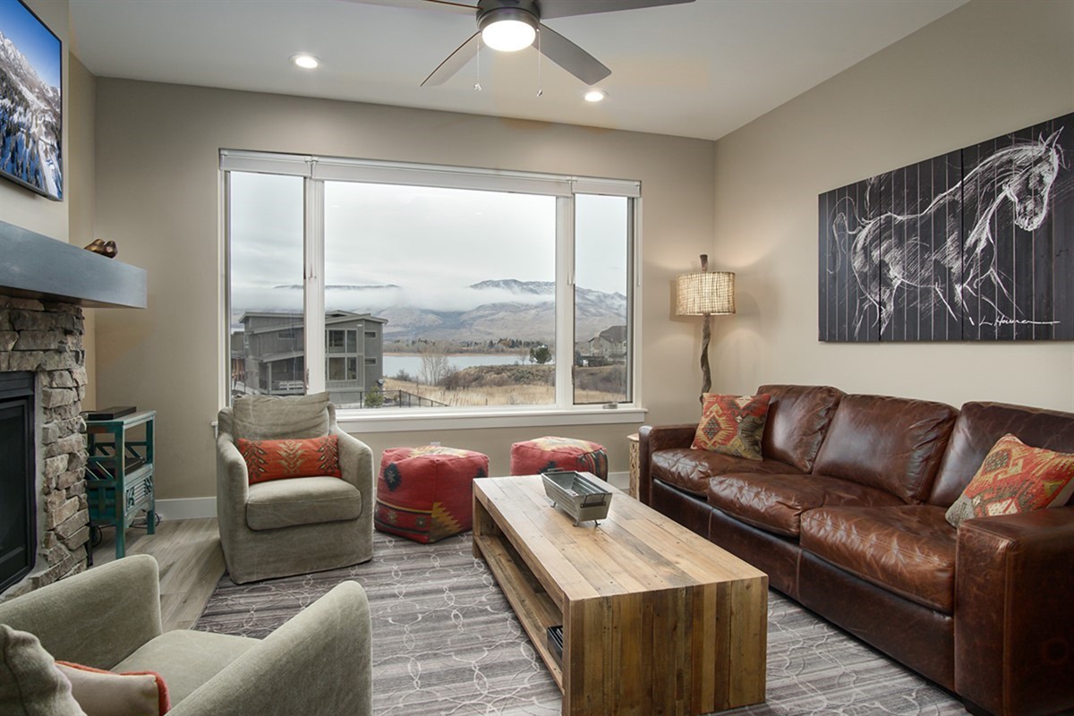 Bright and welcoming living room with cozy fireplace and large windows framing stunning Pineview Reservoir views.