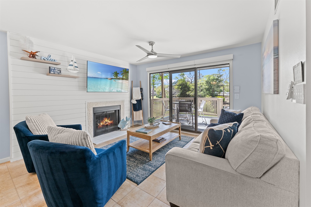 Spacious open Living room with fireplace, large TV and deck access.