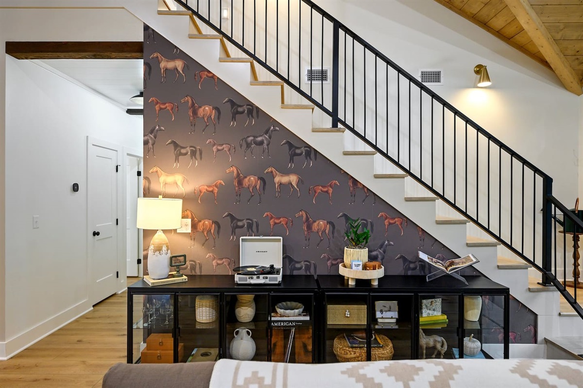 Every detail tells a story — from the custom equestrian wallpaper to the handcrafted metal stair railing, this space blends artful design with timeless character.