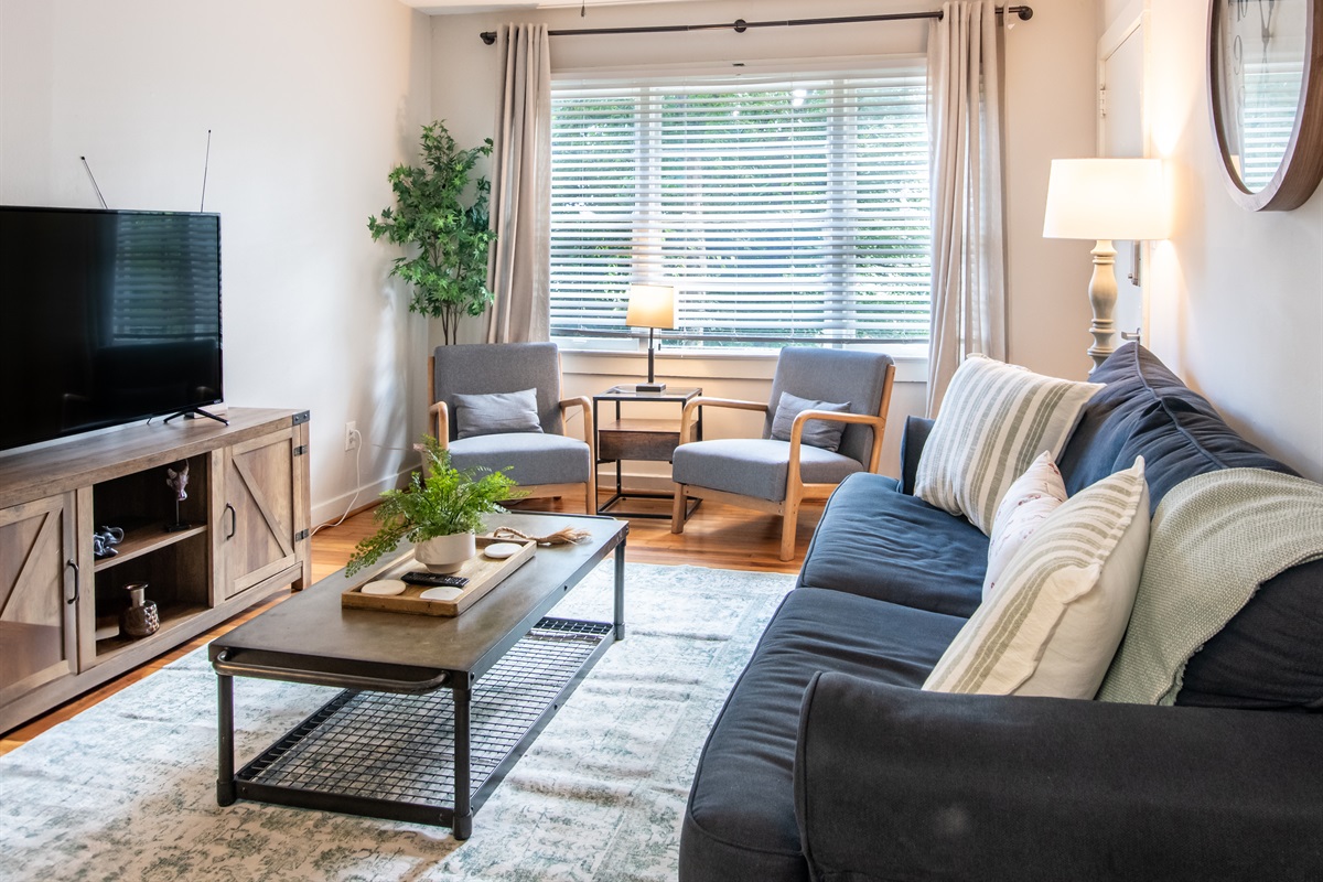 Bright and cozy living room with natural light, a smart TV, and plush seating—perfect for relaxing after a day out.