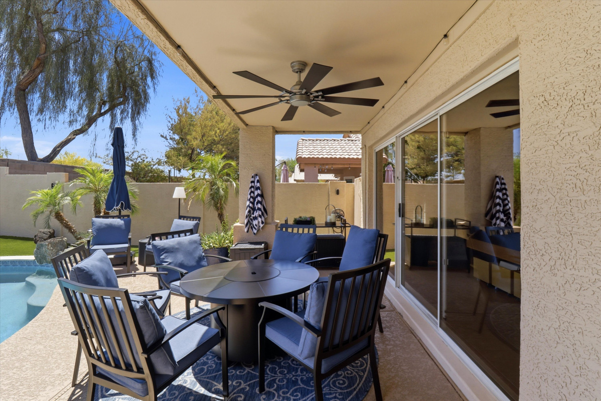 Covered patio dining area with pool views, ceiling fan, and shaded seating for outdoor meals or relaxed downtime.