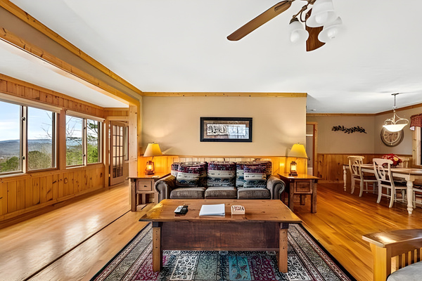 Gather together in the warm and inviting main living area, featuring comfortable seating, a large dining space, and beautiful natural light flowing in from the panoramic windows.