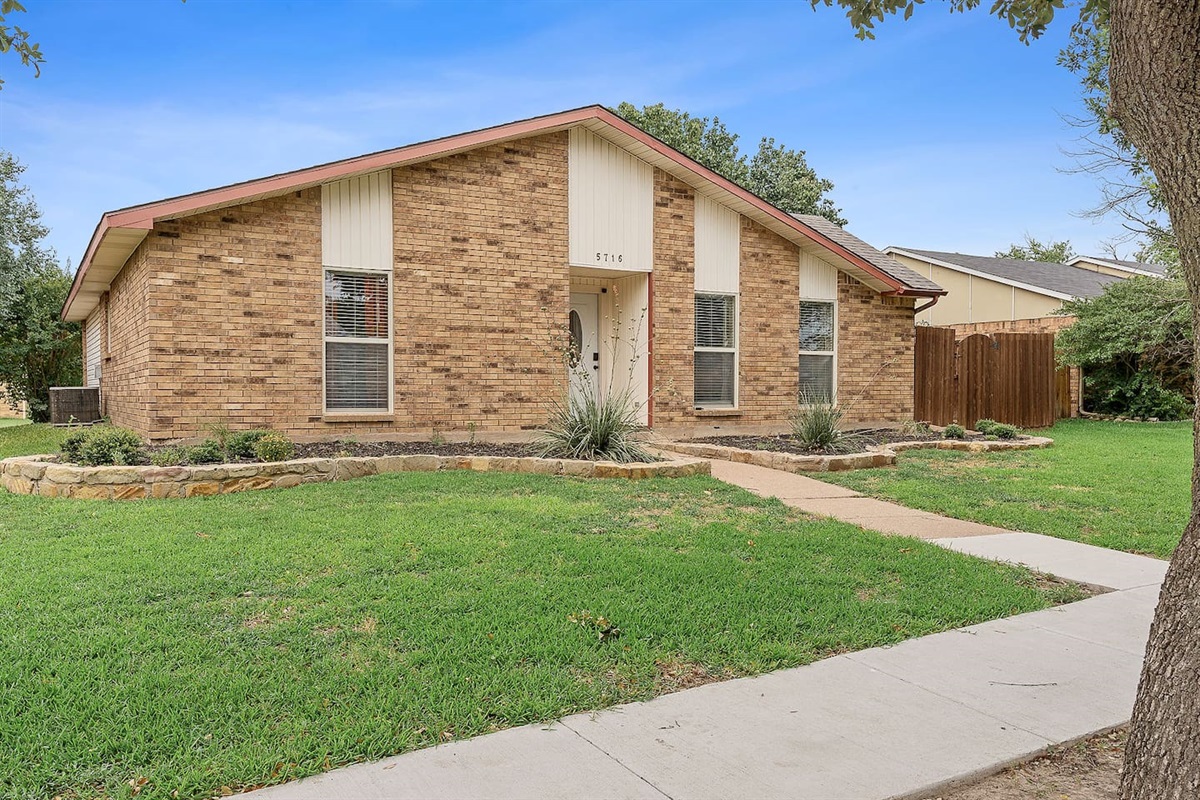 Explore this delightful brick residence featuring a well-maintained lawn and a quaint entry path.


