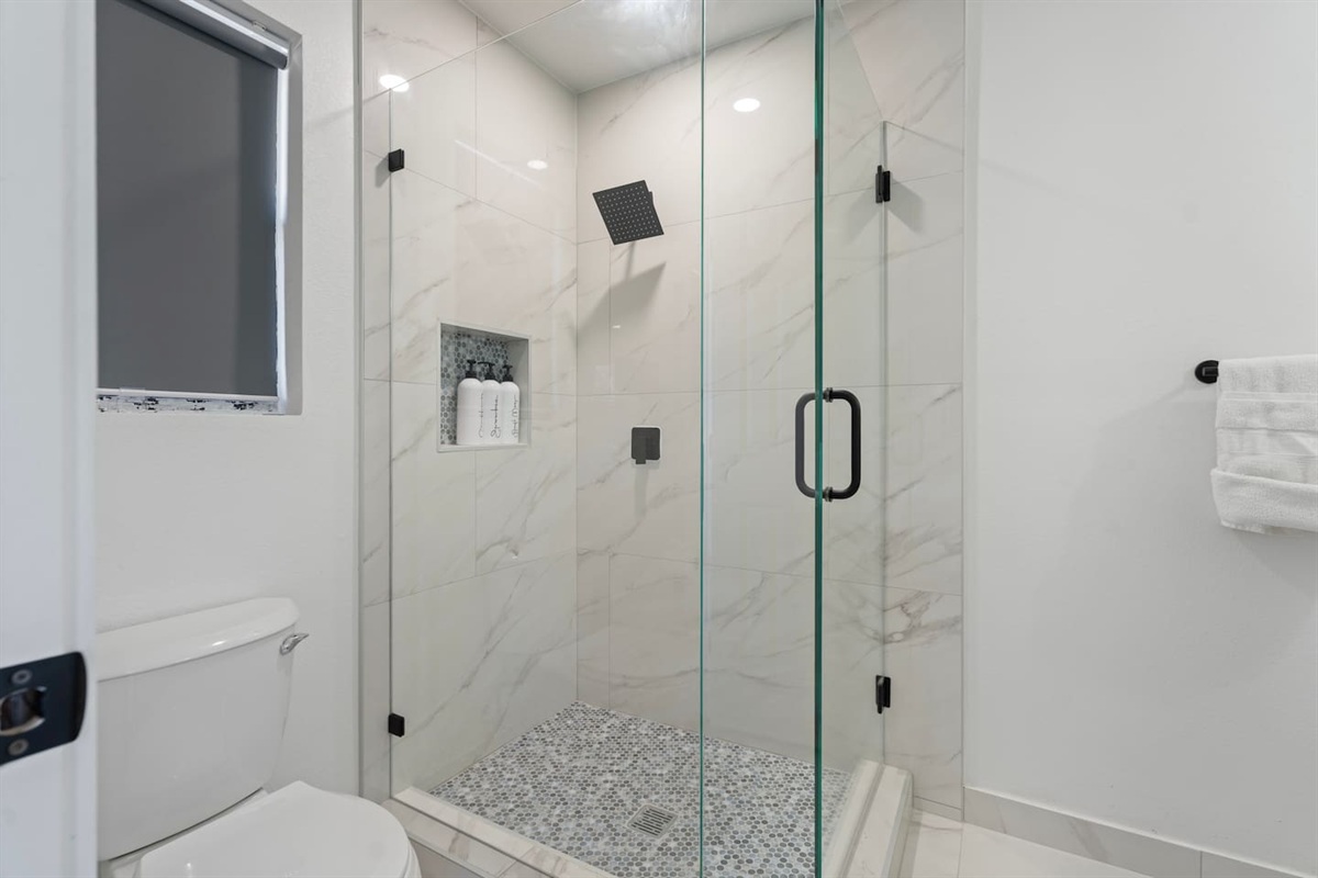 A modern walk-in shower with a rainfall shower head and premium Ginger Lily Farms bath products — a spa-style experience in your Grand Prairie stay.