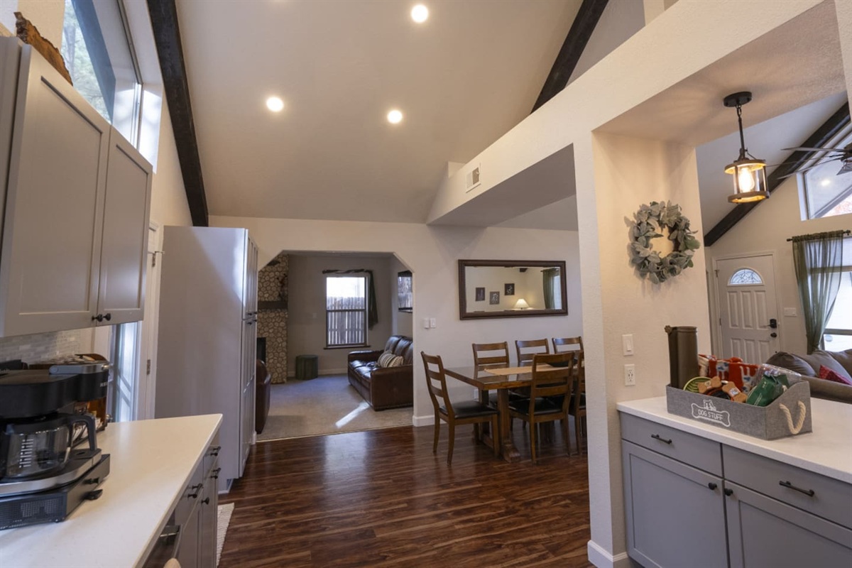Open living room with vaulted ceilings, exposed beams, bar seating, and easy flow into the dining area.