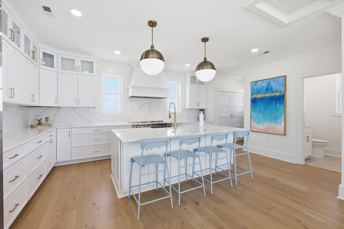 Clean coastal kitchen with oversized island seating and seamless flow into the oceanview living and dining areas