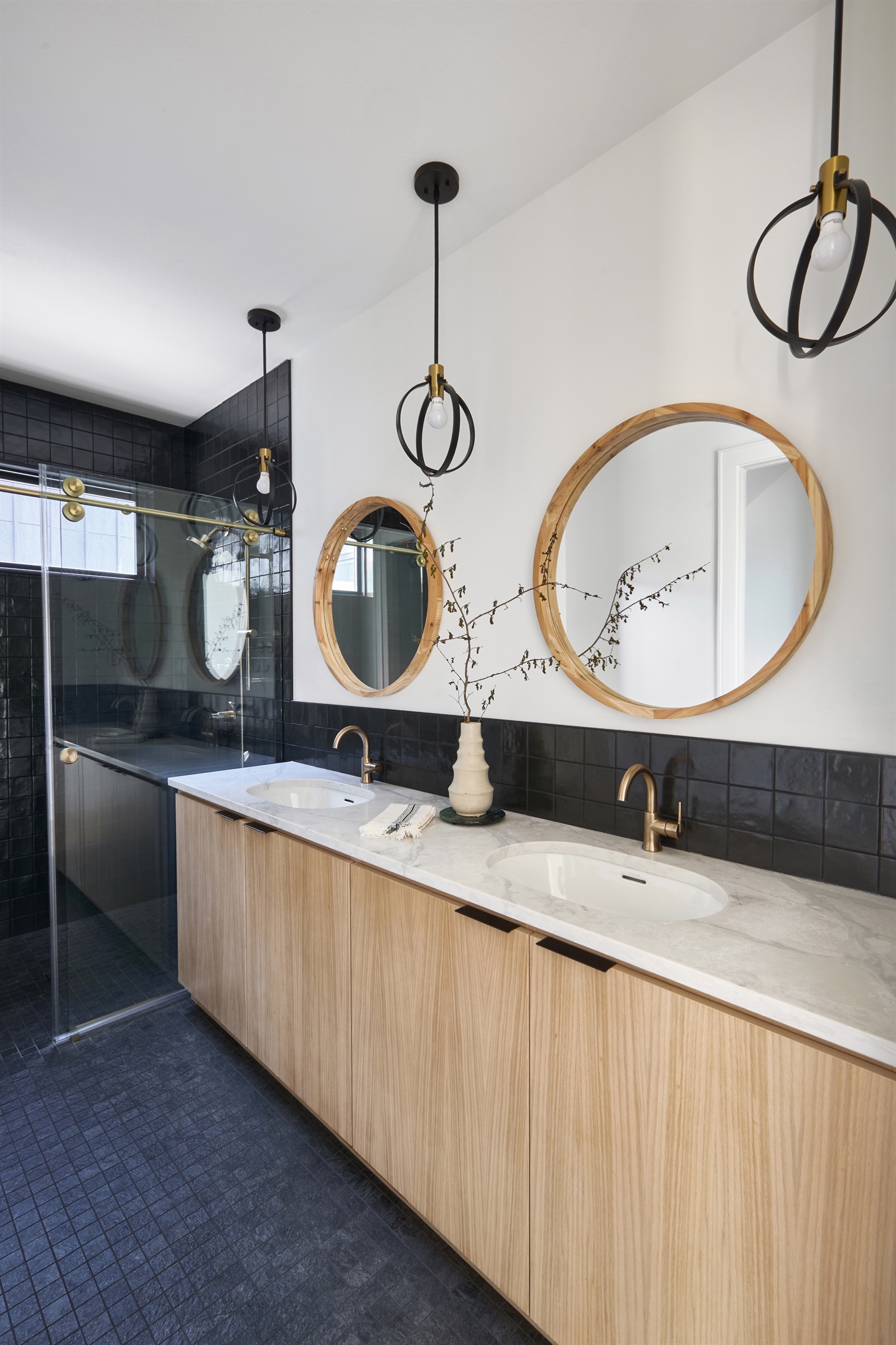 One of four stylish en-suite bathrooms, featuring dual vanities, bold black tile, and brass fixtures for a spa-like retreat.