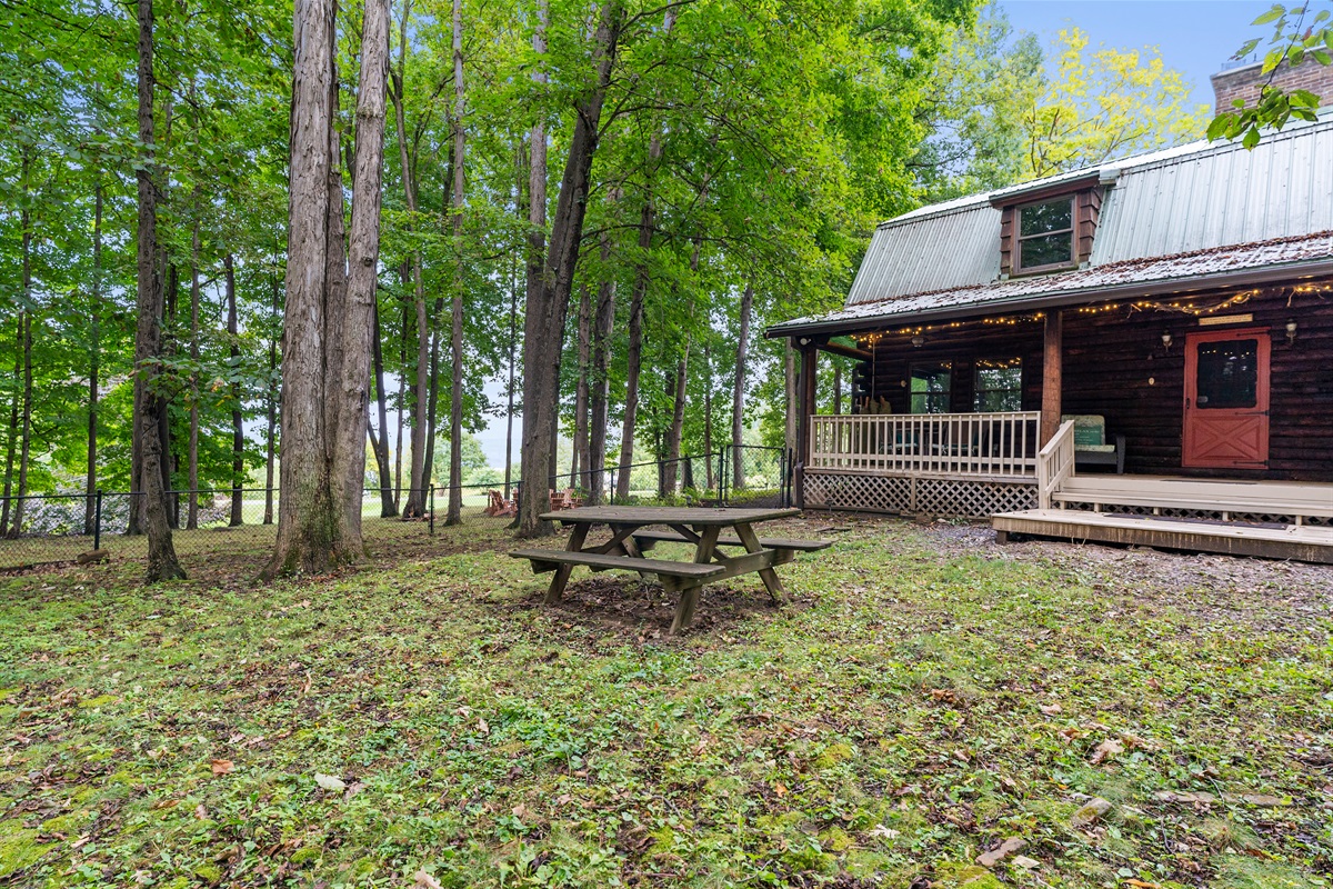 Enjoy the charm of the log cabin with a covered porch, picnic area, and fenced yard surrounded by nature.