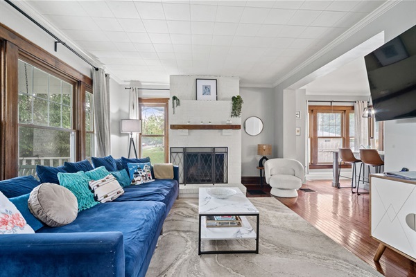 An oversized sofa complements the beautiful windows that fill the living room with natural light, highlighting the stunning features of this fully remodeled 100-year-old home.