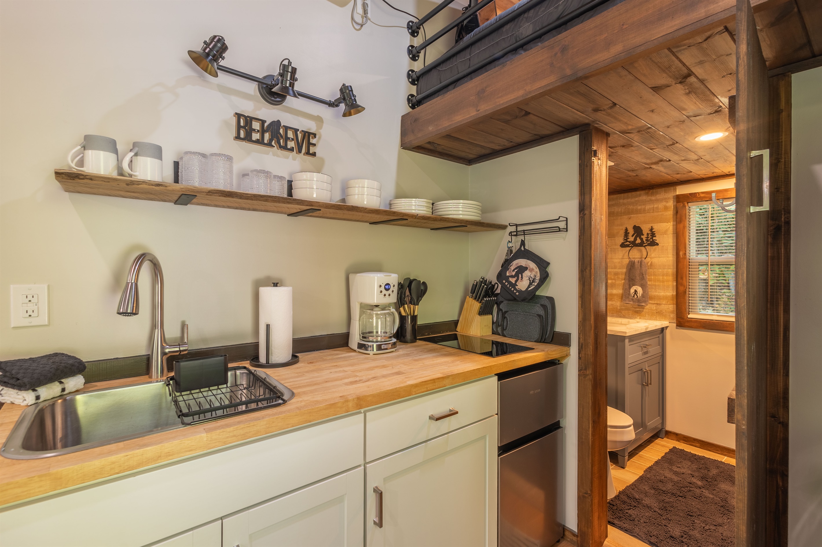 Smart tiny home design with a kitchenette, mini fridge, and full bathroom just beyond.