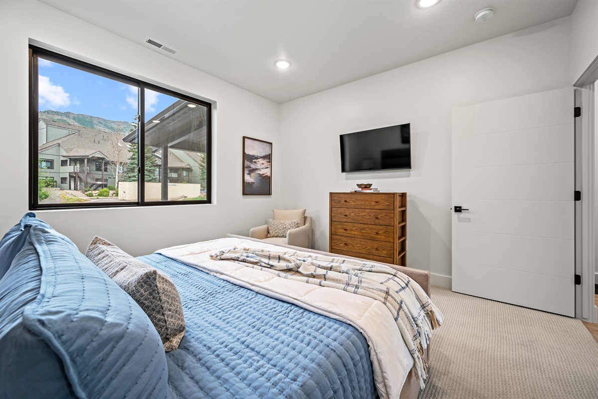 Unwind in a cozy king bed with plush bedding, a flat-screen TV, and a dresser for convenient storage.